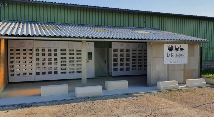 Casiers de produits locaux devant un bâtiment agricole vert